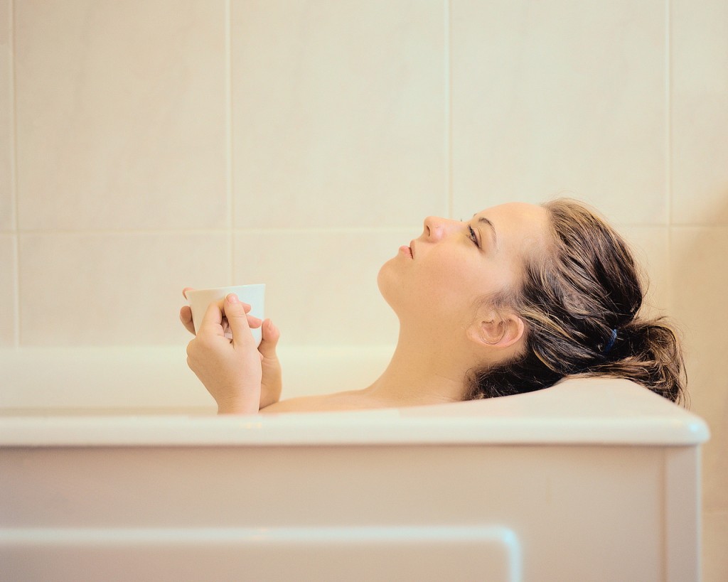 Woman Lying in a Bathtub Holding a Mug cleanliness of woman in tub
