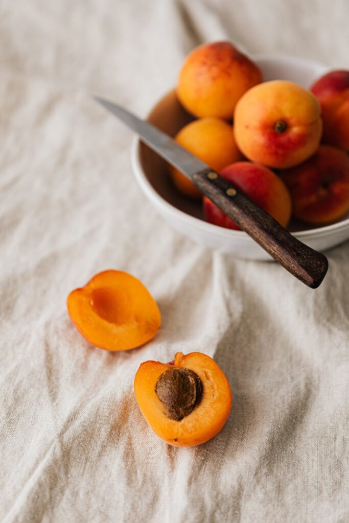 locally grown peaches in a white bowl with sharp knife