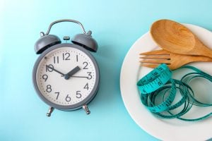 clock next to plate with tape measure and spoon