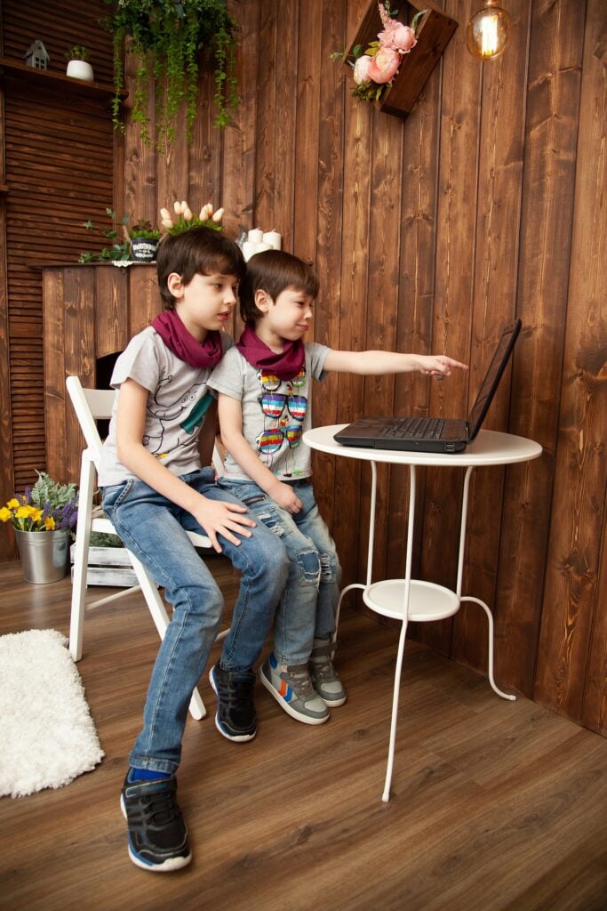 two kids watching the screen of a computer