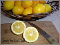 wooden basket full of fresh lemons with cut lemon on cutting board