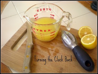 fresh lemon juice in glass measuring cup on cutting board with fresh lemon and kitchen utensils