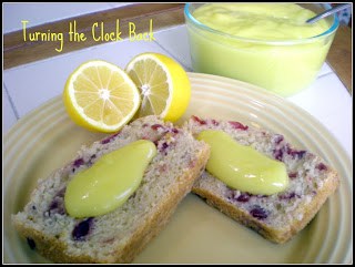 easy lemon curd recipe in bowl near plate of cranberry bread topped with lemon curd