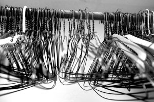 Many several metal wire hangers on pole for hanging clothing in closet storage