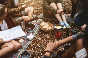 adults sitting outside camping