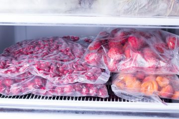Frozen berries and fruits in bags in freezer, close up. Stocks of meal for the winter.