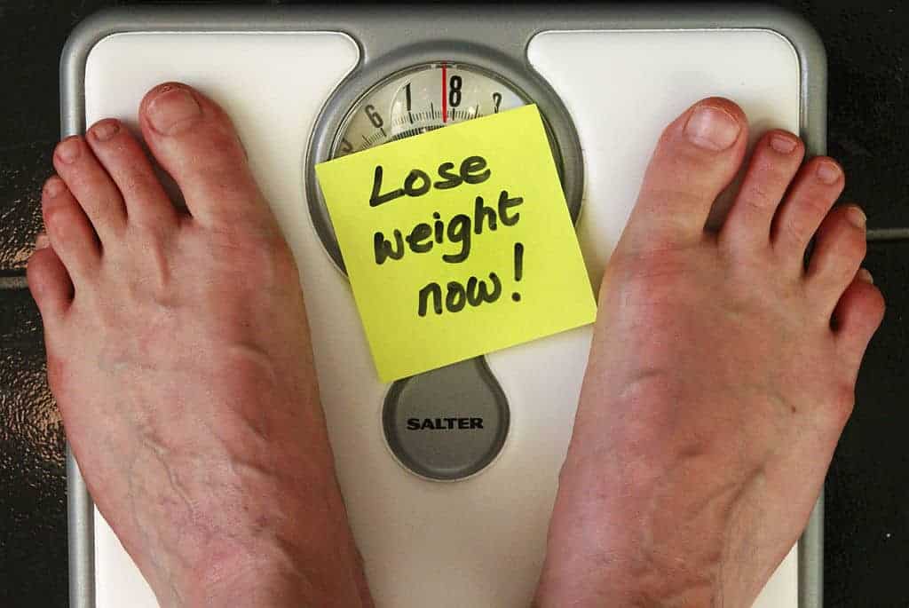 feet on a scale with note that says lose weight now