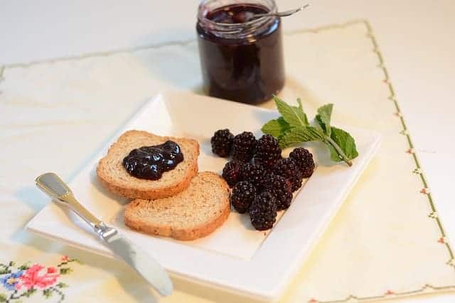 blackberry jam on toast on white plate with fresh blackberries