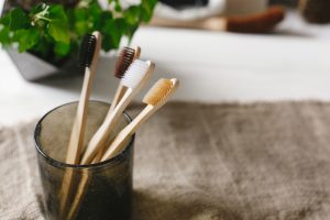 clean eco natural bamboo toothbrushes in glass on rustic background wi