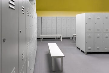 Row of steel lockers along the yellow wall and white benches