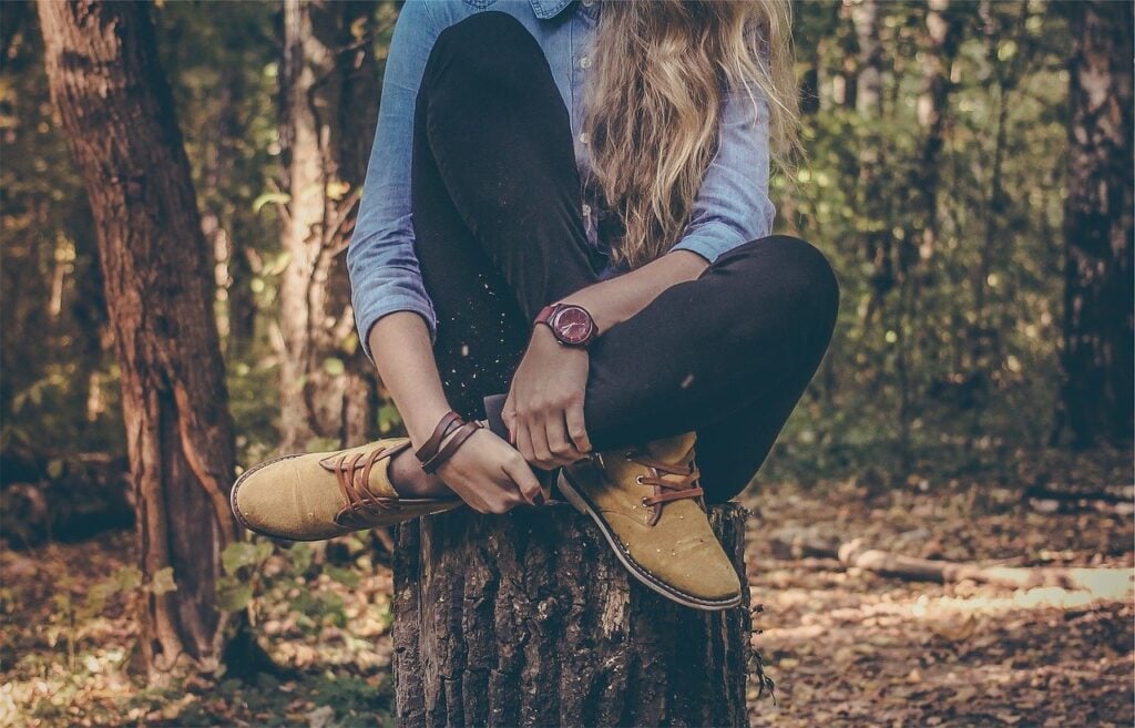 woman sitting on tree stump in rustic clothes