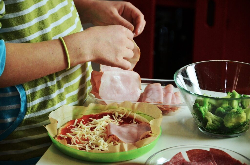 parent cooking homemade pizza with child