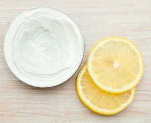 body cream and lemon slices on the wooden table. top view
