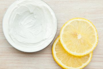 body cream and lemon slices on the wooden table. top view