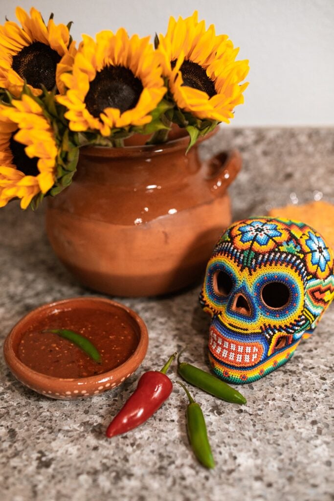 homemade hot sauce with hot peppers next to it