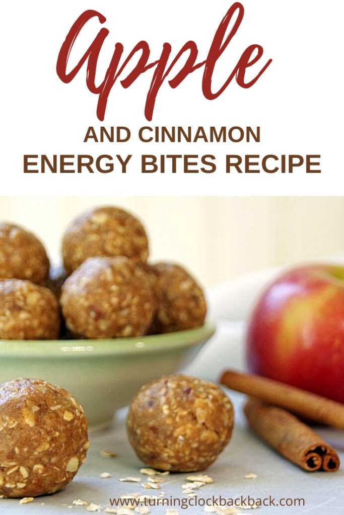 Apple and cinnamon energy bites in a small bowl with fresh apple and cinnamon stick