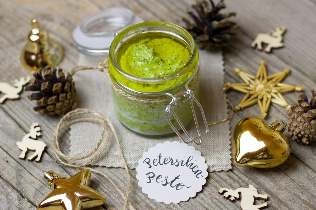 pesto as a homemade Christmas gift with holiday decorations around it. 