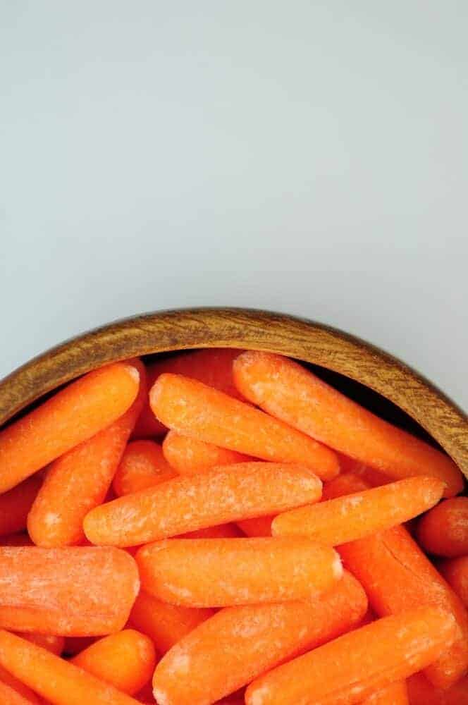 Fresh Small Orange Carrots in Wood Bowl.