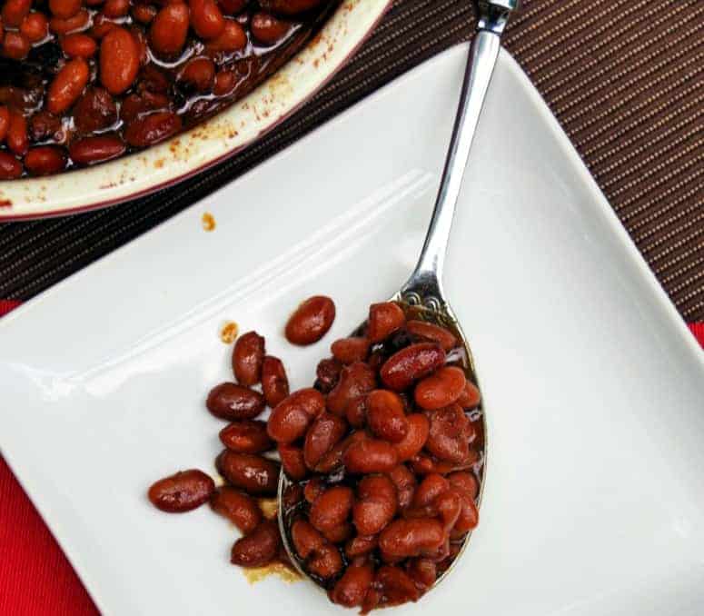 New England Style Homemade Baked Beans from Scratch in a ceramic pot with metal spoon