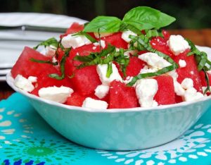 watermelon salad with feta and basil in a white bowl and blue napkin