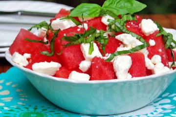 watermelon salad with feta and basil in a white bowl and blue napkin