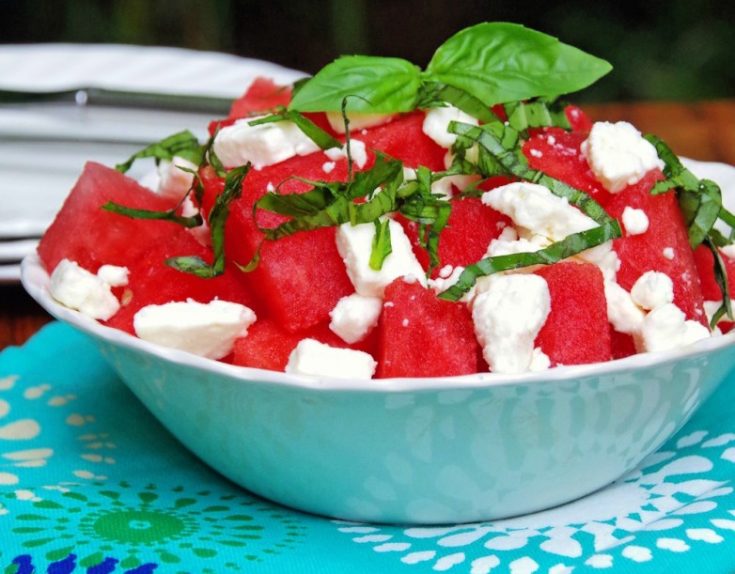 watermelon salad with feta and basil in a white bowl and blue napkin
