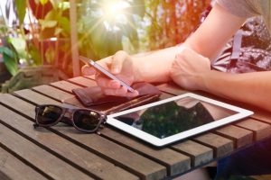 hands holding iphone with ipad on table outside