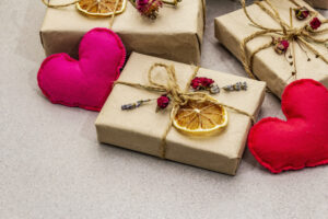 Zero waste gift concept. Valentine Day or Birthday eco friendly packaging. Festive boxes in craft paper with different organic decorations. Stone concrete background