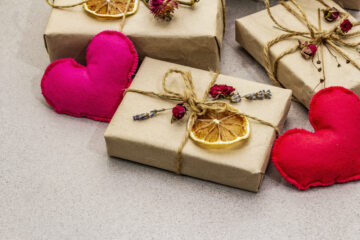 Zero waste gift concept. Valentine Day or Birthday eco friendly packaging. Festive boxes in craft paper with different organic decorations. Stone concrete background