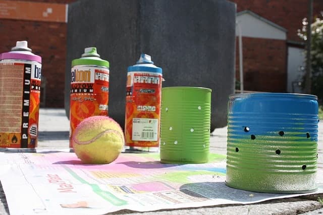 old tin cans and spray paint on newspaper for crafting