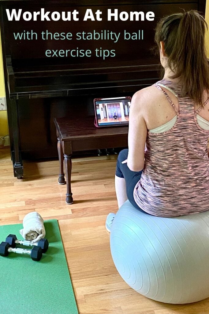 middle aged woman sitting on exercise ball at home watching exercise ball workout on ipad