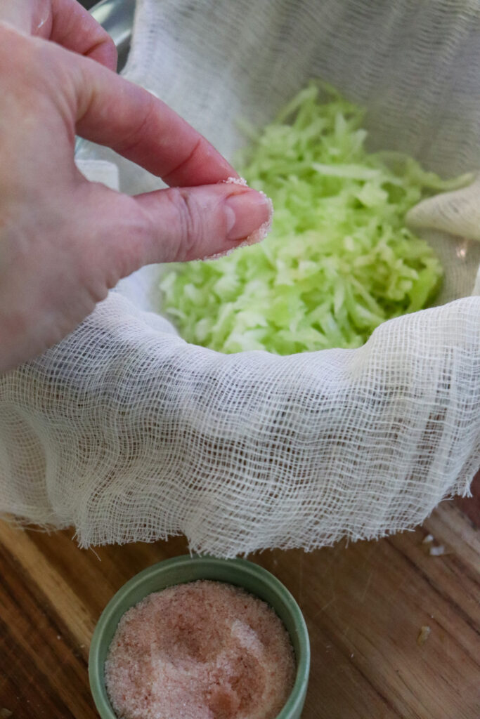 shredded cucumber in strainer being salted