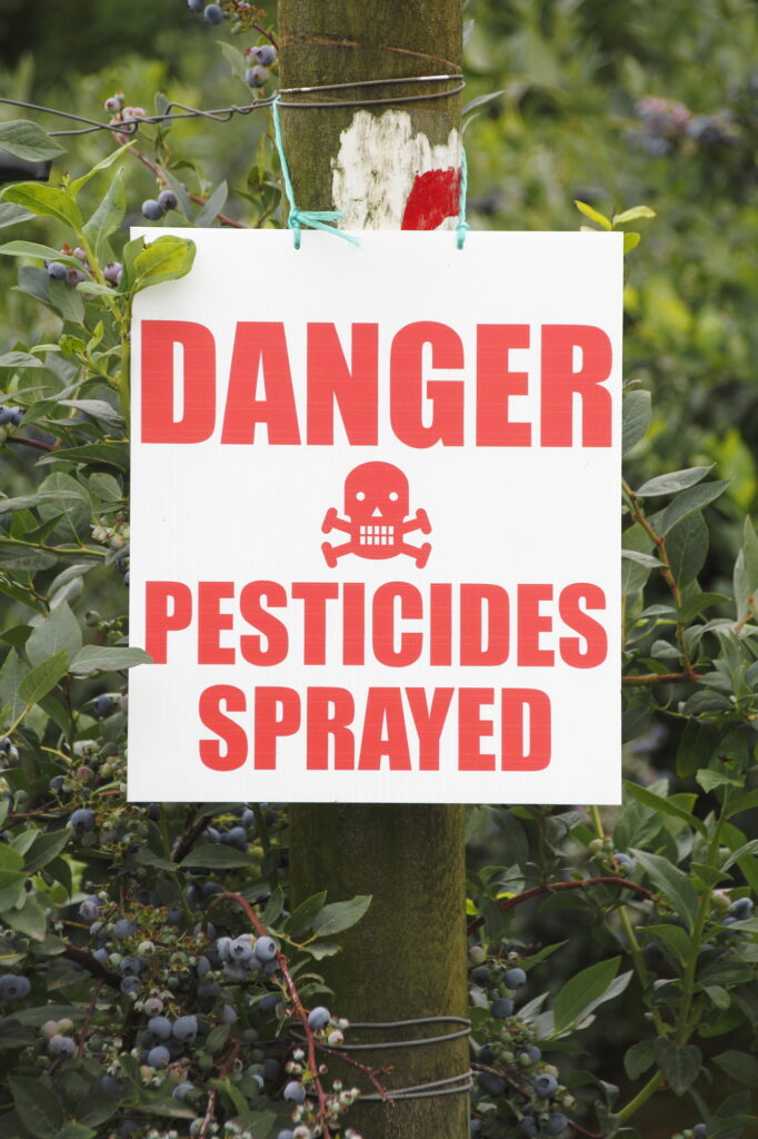 yard with sign stating danger pesticides sprayed