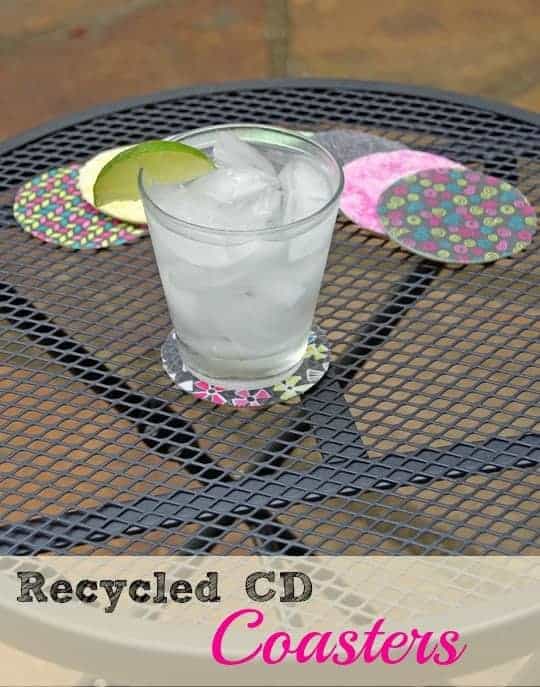 pile of upcycled CDs on a table with a CD coaster under a glass of water