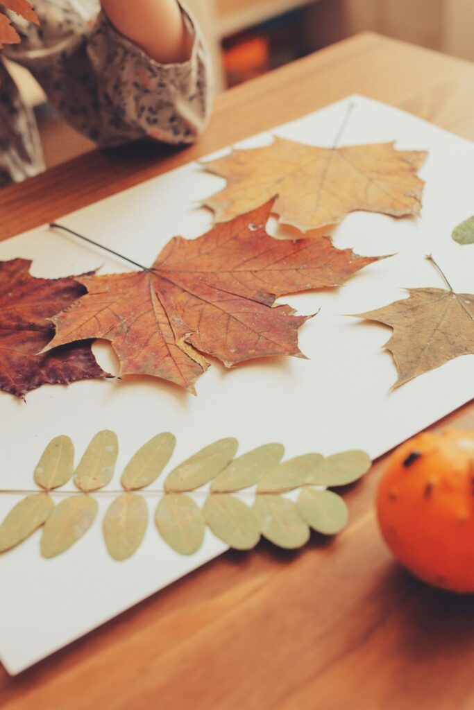 child doing leaf crafts on a table
